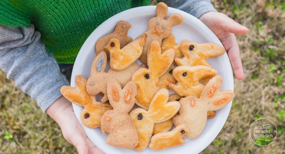Fertig gebackene Osterhasen-Kekse mit simpler Eigelbglasur und Rosinenaugen
