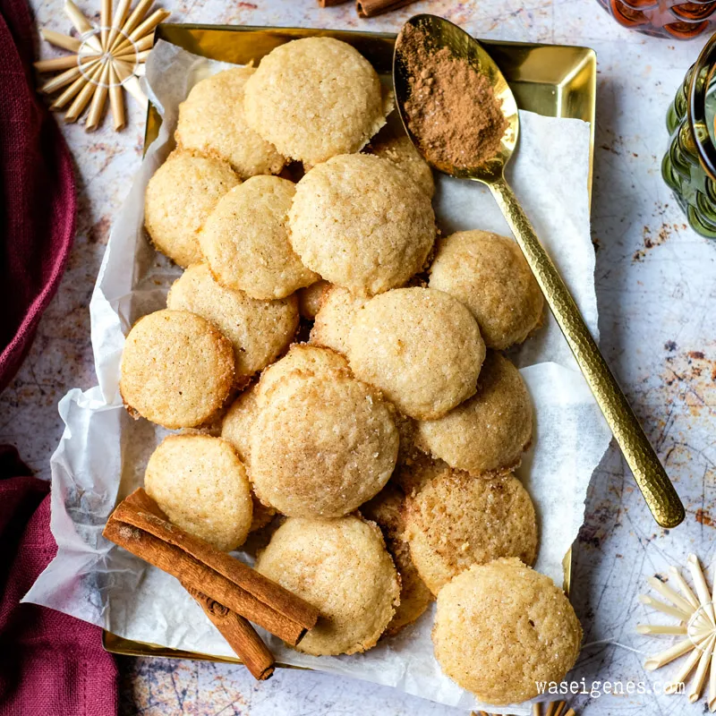 Fertig gebackene Zimtsterne auf einem Teller, bestreut mit Zimt und Zucker