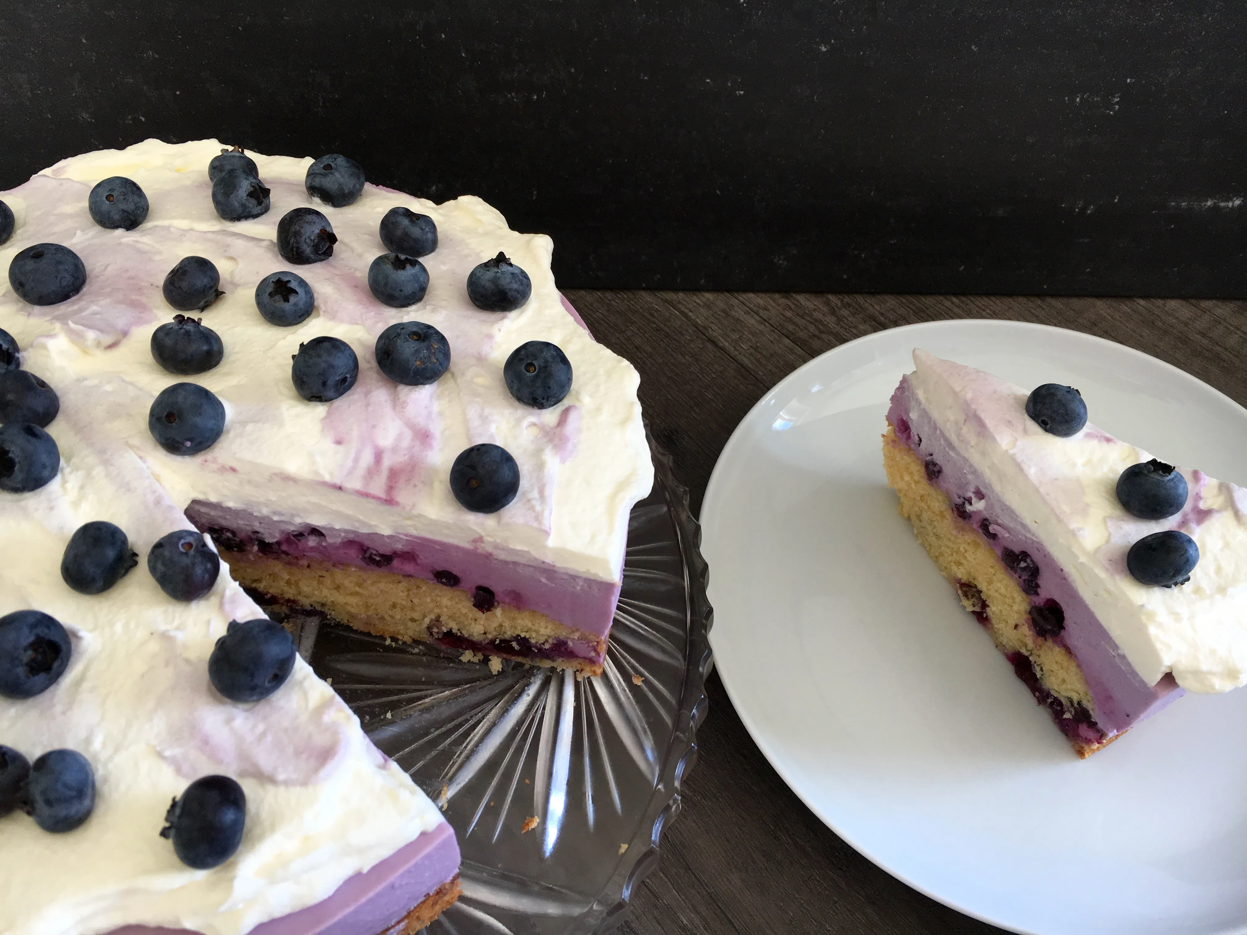 Fertig verzierte Käsesahne-Torte mit Sahnetopping und frischen Blaubeeren