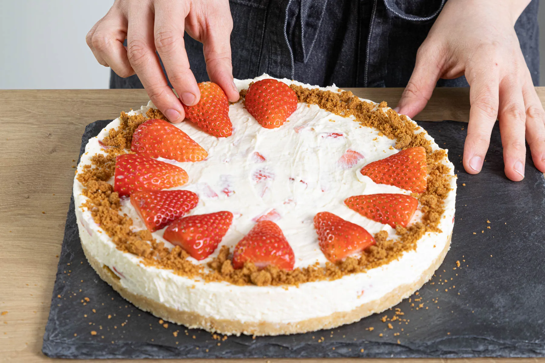 Fertige Philadelphia-Erdbeer-Frischkäse-Torte mit frischen Erdbeeren und Keksbröseln dekoriert