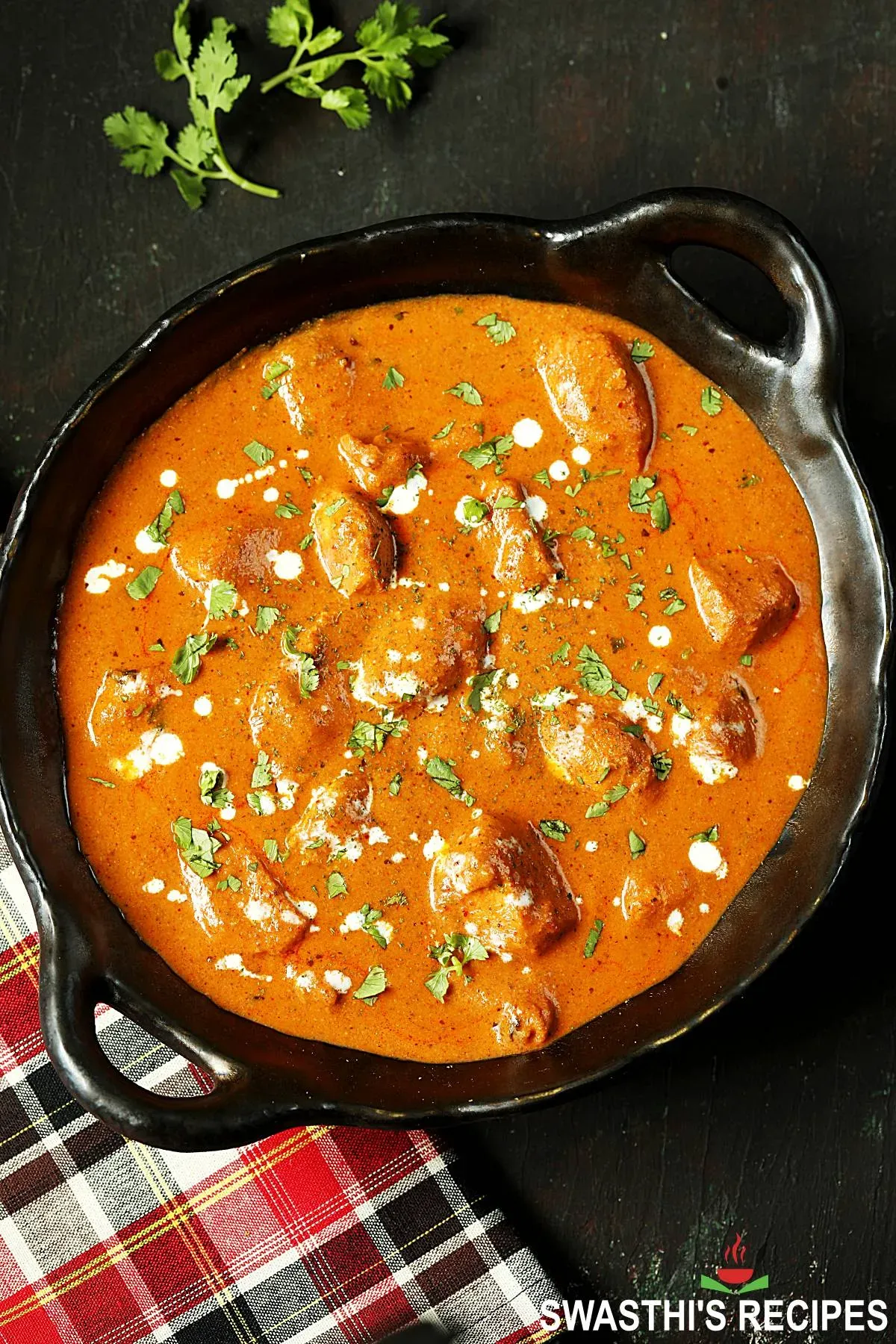 Fertiges Butter Chicken in einer Schale serviert, garniert mit Koriander und Sahne.