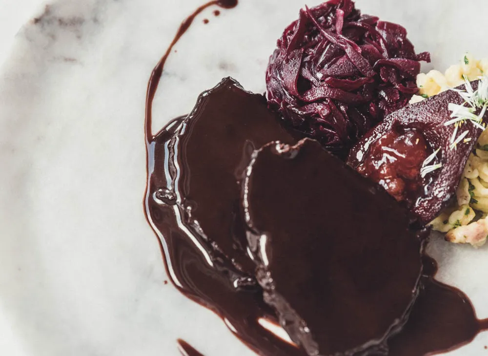 Festlich angerichteter Hirschbraten mit Spätzle und Blaukraut auf einem Teller