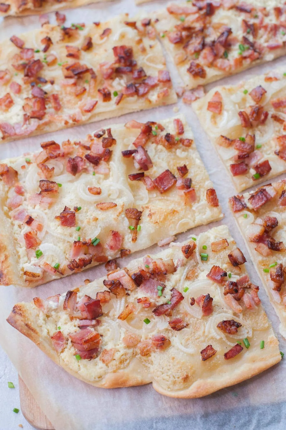 Flammkuchen in Quadrate geschnitten auf Backpapier
