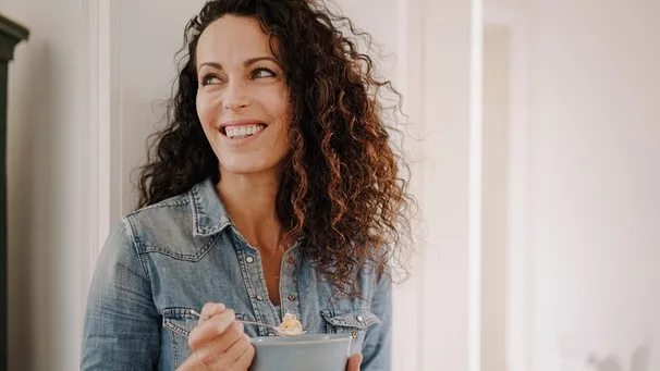 Frau isst genüsslich eine Schüssel Müsli mit Haferkleie und frischen Früchten