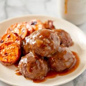 Frikkadels auf einem weißen Teller mit Süßkartoffel.