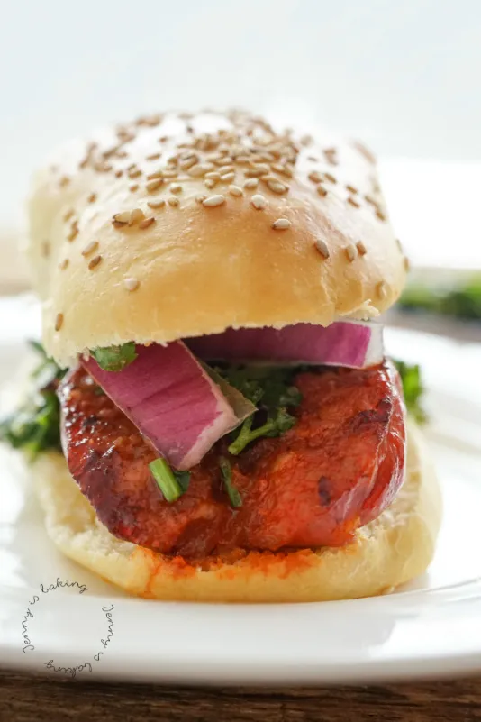 Frisch gebackene Choripán, ein argentinischer Hot Dog, mit hausgemachten Hot Dog Brötchen und Chimichurri-Soße auf einem Holzbrett angerichtet