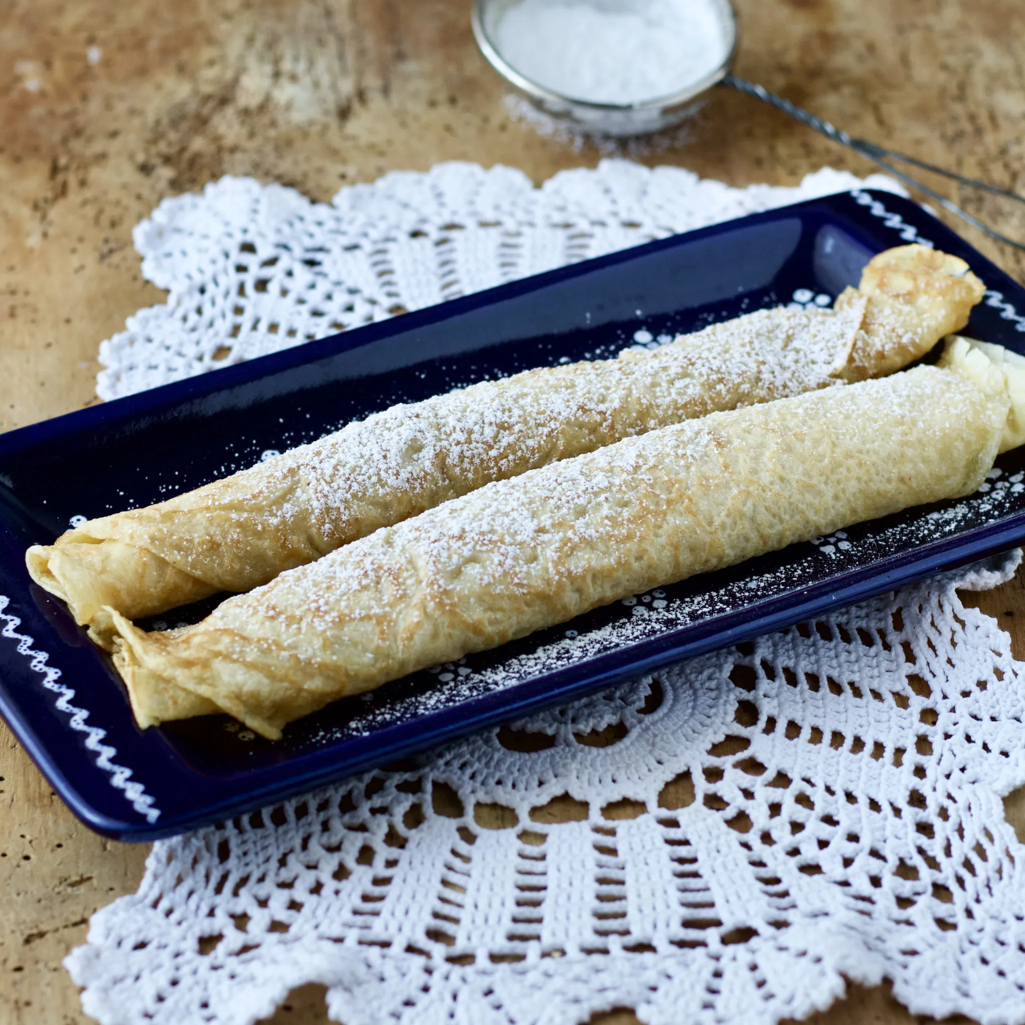 Frisch gebackene, gestapelte Palatschinken mit Marmeladenfüllung und Puderzucker bestreut