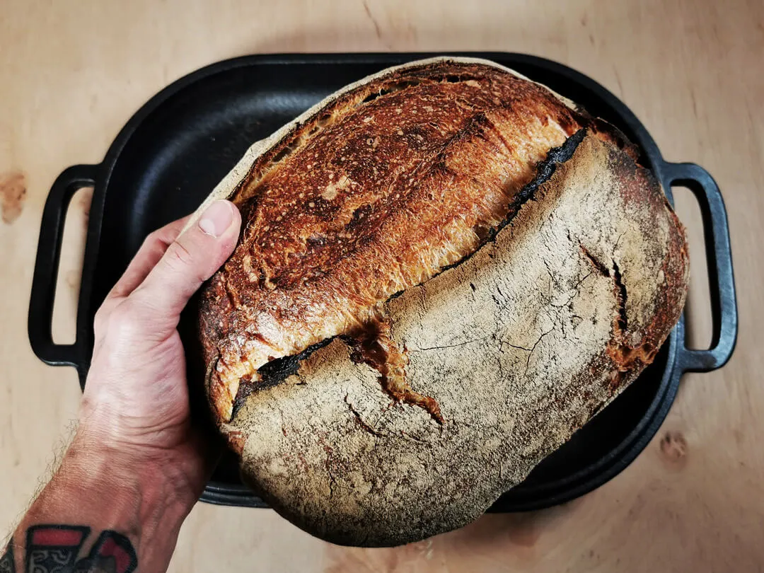 Frisch gebackenes Sauerteigbrot mit goldbrauner Kruste auf einem Holzbrett