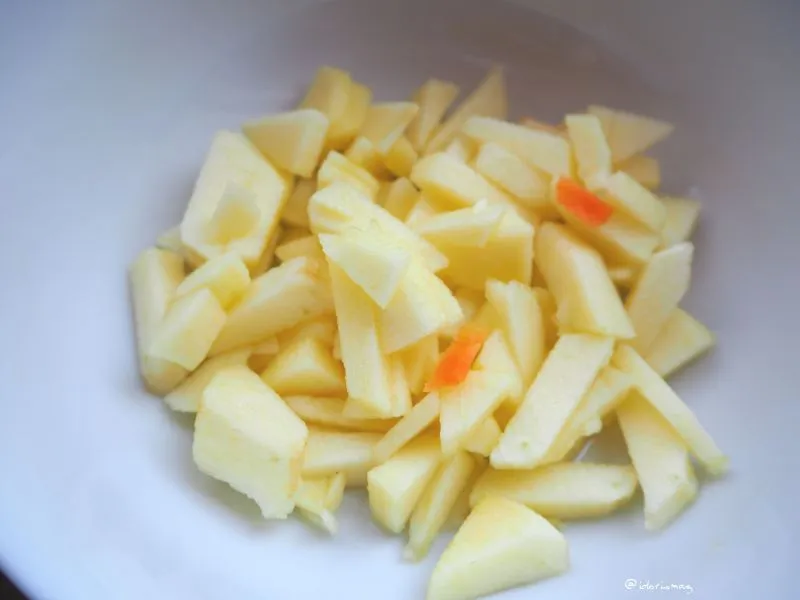 Frisch geschnittene Äpfel, Karotten und Zitronenhälften auf einem Schneidebrett, bereit zur weiteren Verarbeitung