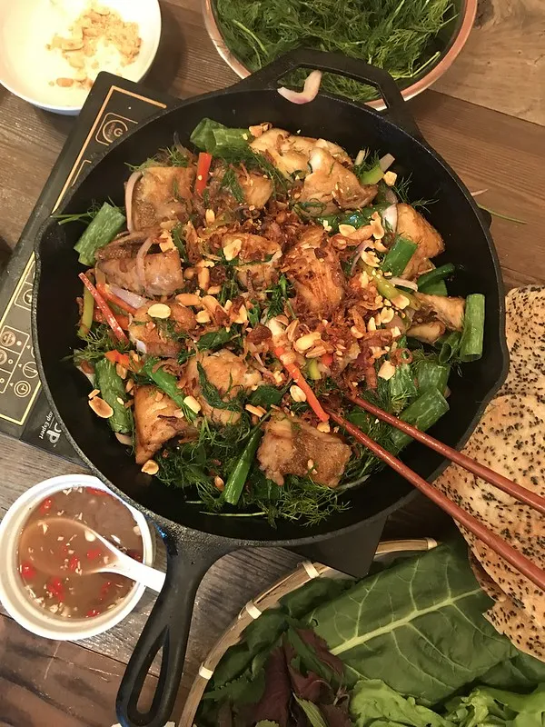 Frisch zubereiteter Cha Ca Thang Long auf heißer Platte mit Dill und Lauchzwiebeln