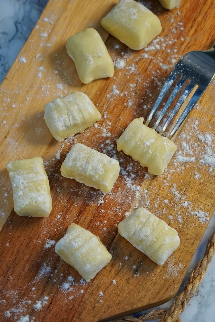 Frisch zubereiteter Gnocchi-Teig auf einem bemehlten Holzbrett, bereit zum Formen
