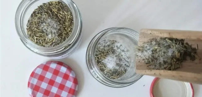 Frisch zubereitetes Kräutersalz in einer Schale mit verschiedenen getrockneten Kräutern