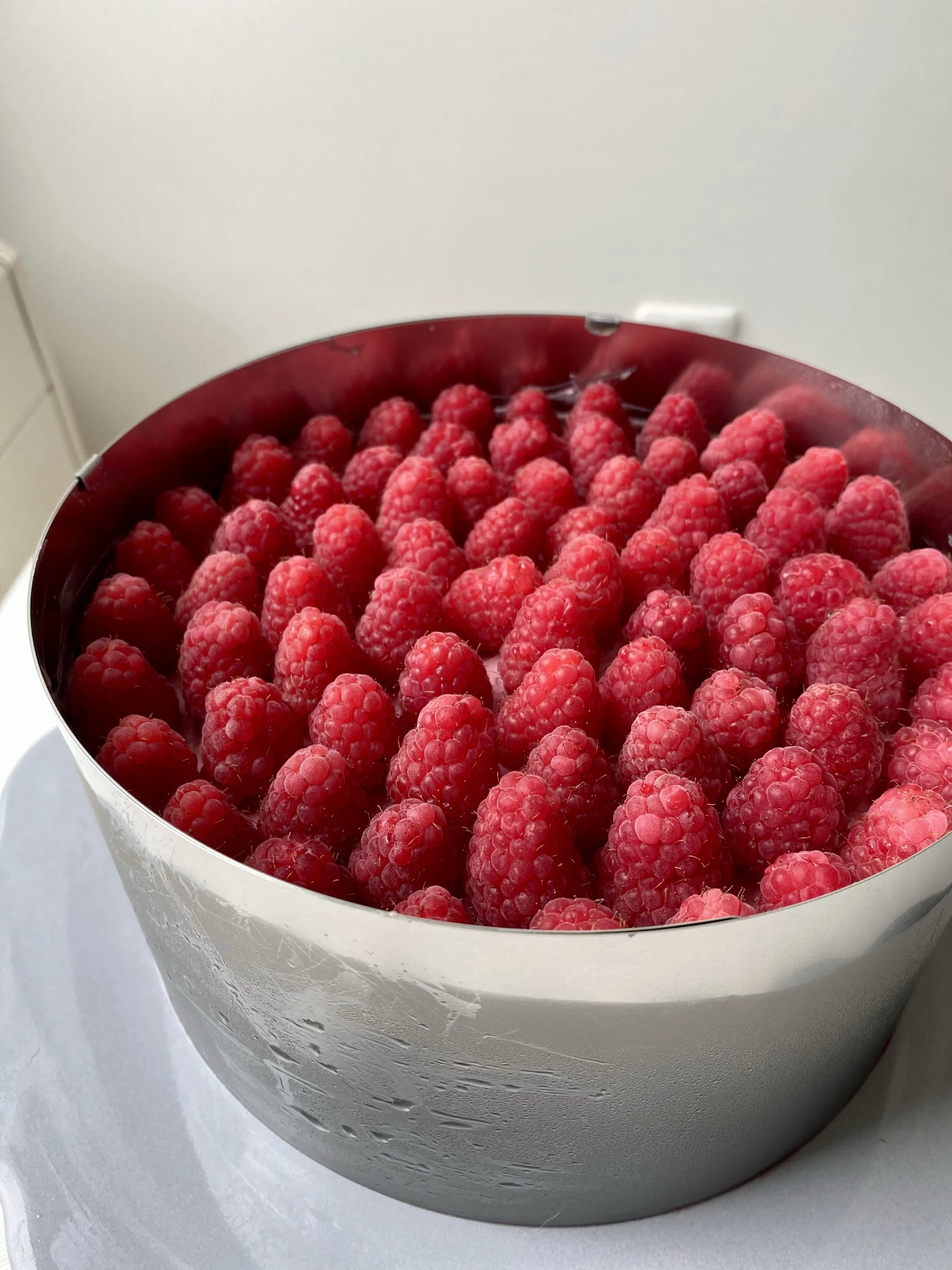 Frische Himbeeren werden auf der veganen Himbeer Sahne Torte arrangiert, bevor das Gelee darüber gegossen wird.