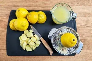 Frischen Ingwer schälen und in Stücke schneiden, daneben aufgeschnittene Zitronen