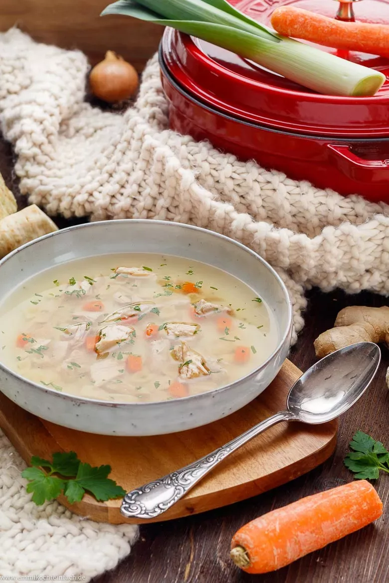 Frisches Suppengemüse und eine Zwiebel als essentielle Zutaten für die Hühnersuppe