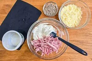 Füllung mit Frischkäse, Kochschinken und Bergkäse für den gebackenen Kürbis und separat Sonnenblumenkerne vorbereiten