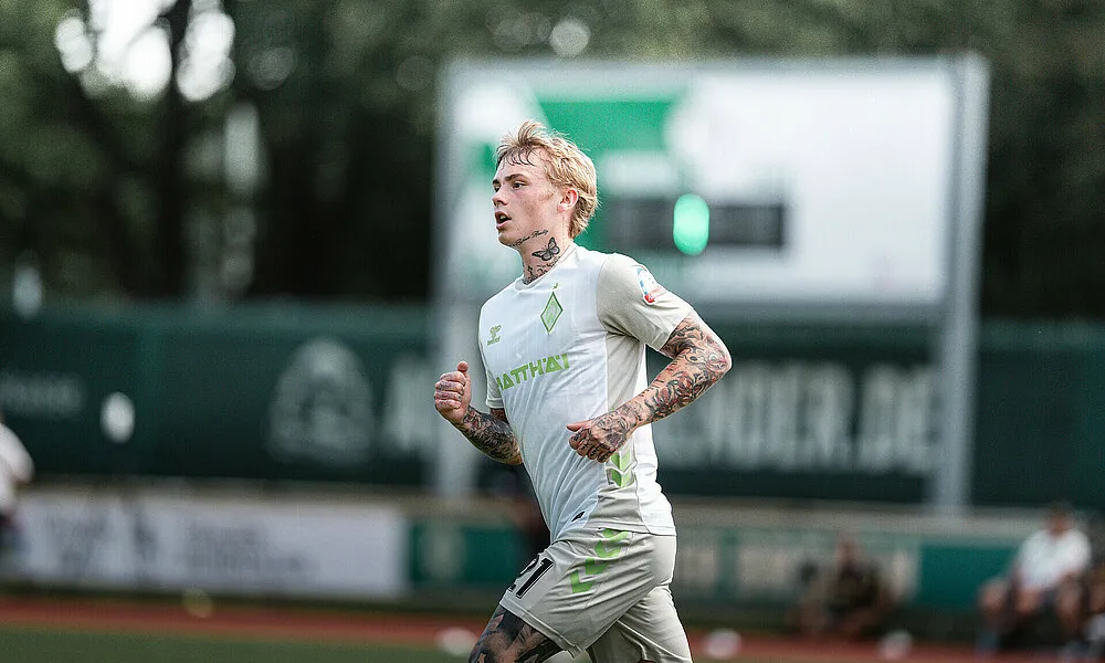 Fußballspieler in Aktion im grünen Trikot auf dem Trainingsplatz während eines Testspiels