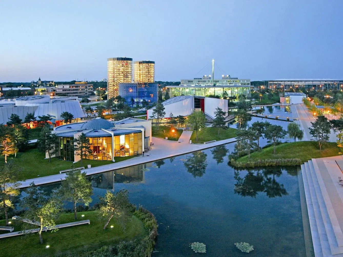 Futuristische Gebäude der Autostadt Wolfsburg bei Abenddämmerung, Spiegelungen im Wasser