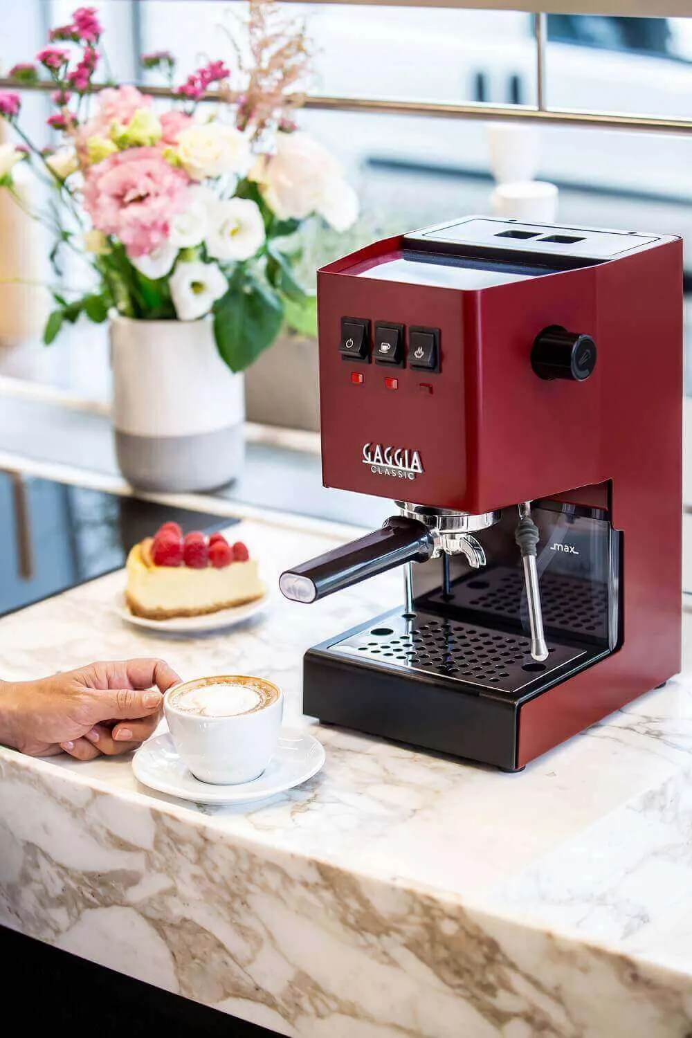 Gaggia New Classic in Sherry Red mit Blumen im Hintergrund