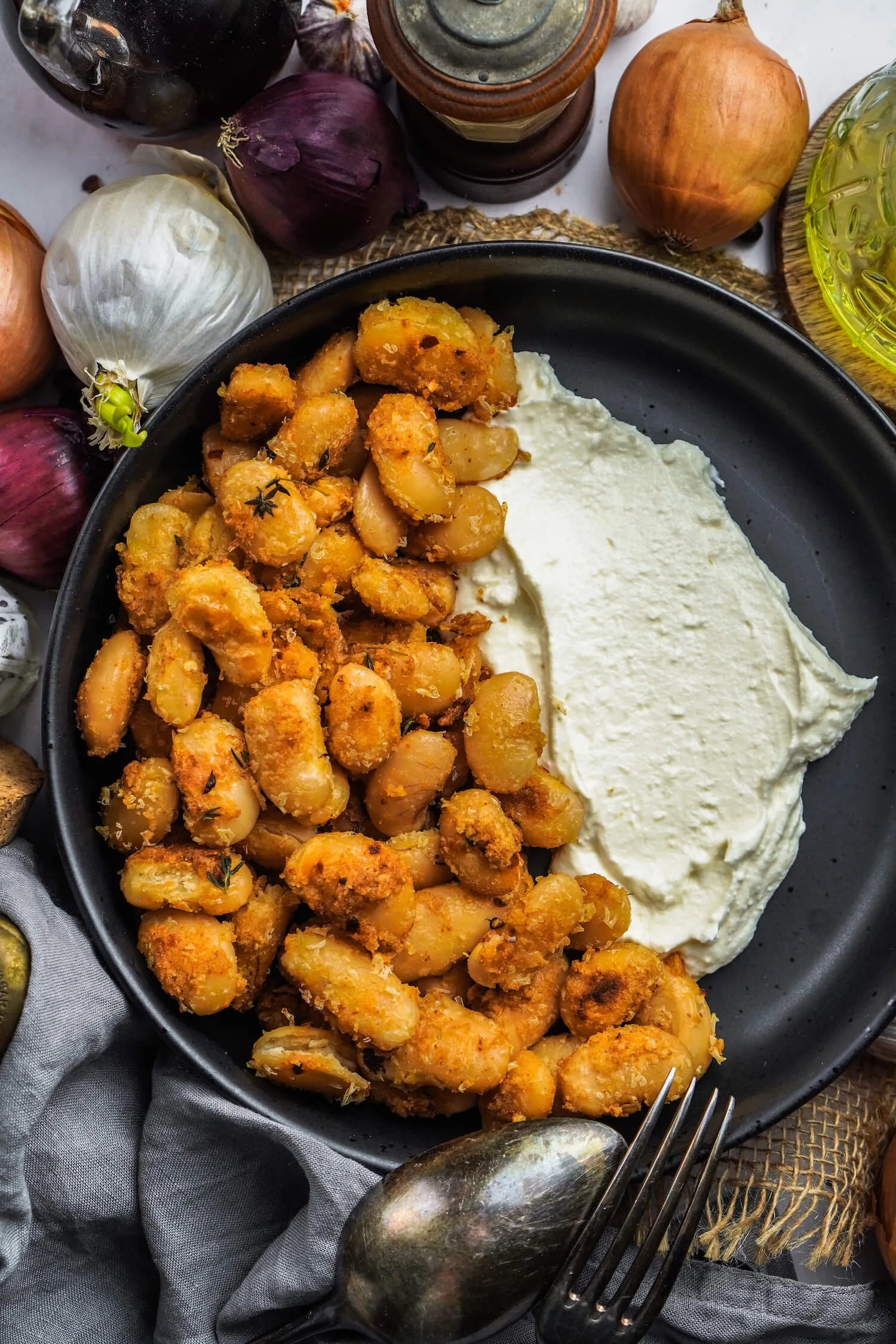 Gebackene Bohnen mit Feta Creme in einer rustikalen Schale auf Holzuntergrund