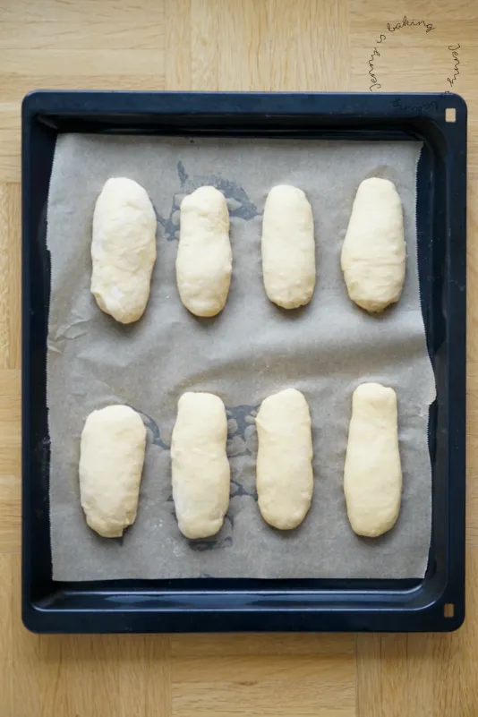 Geformter Hefeteig für Hot Dog Brötchen, auf Backpapier bereit zum Gehen und Backen