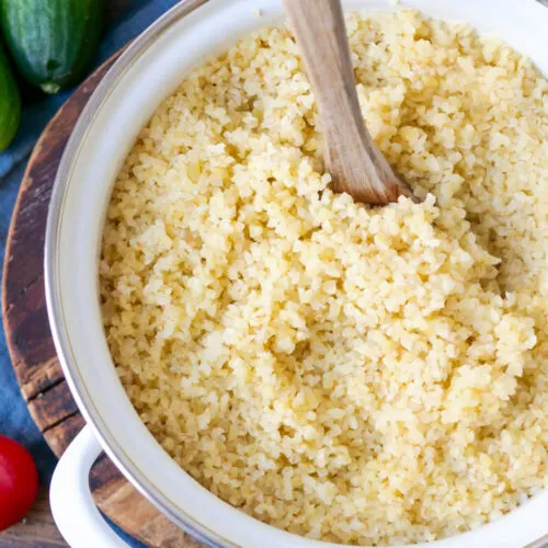 Gekochter Bulgur in einem Topf mit einem Holzkochlöffel, fertig zum Servieren.