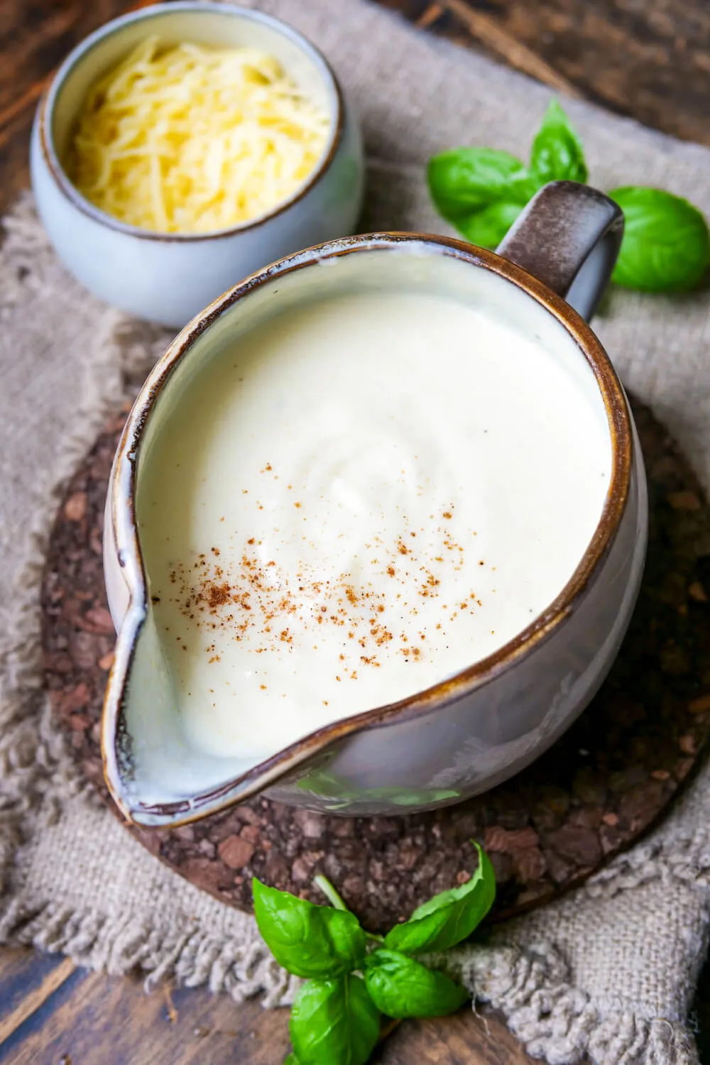 Geriebener Käse und Milchkanne neben der cremigen Käsesoße