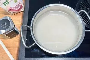 Gewaschenen Reis und Salz in einen Kochtopf geben