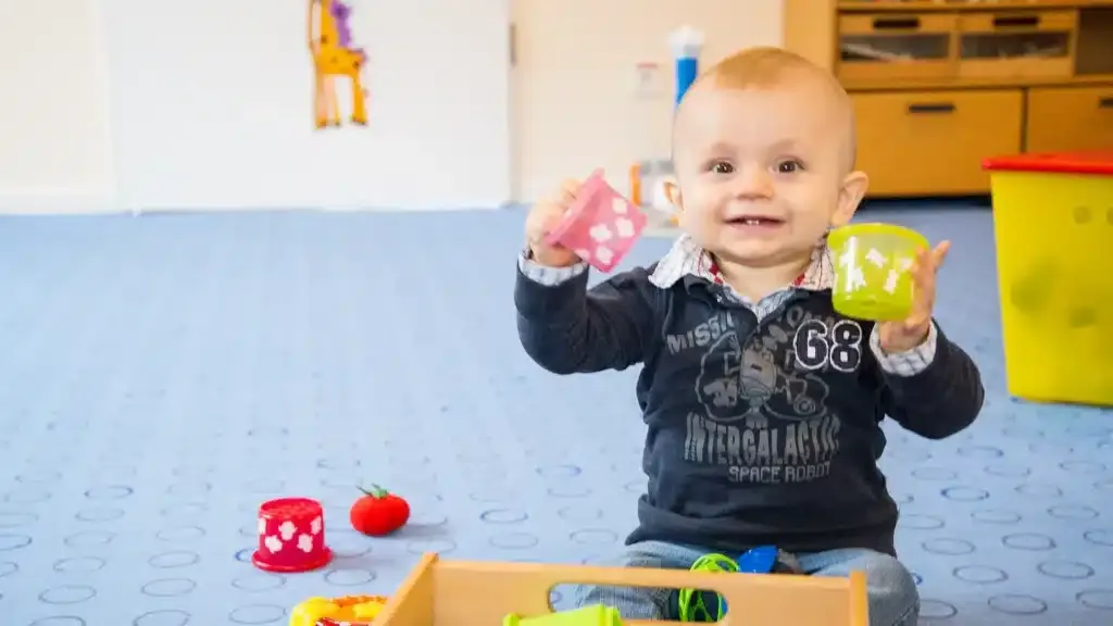 Glückliches Baby spielt in einem Babyzimmer mit bunten Spielsachen