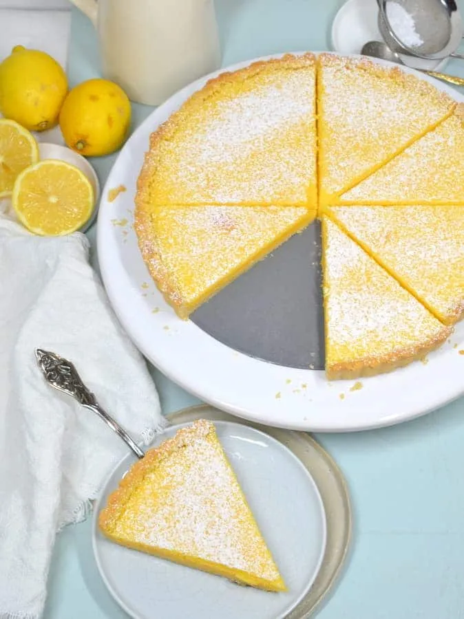 Goldbraune Zitronentarte auf einem blauen Teller, verziert mit Puderzucker