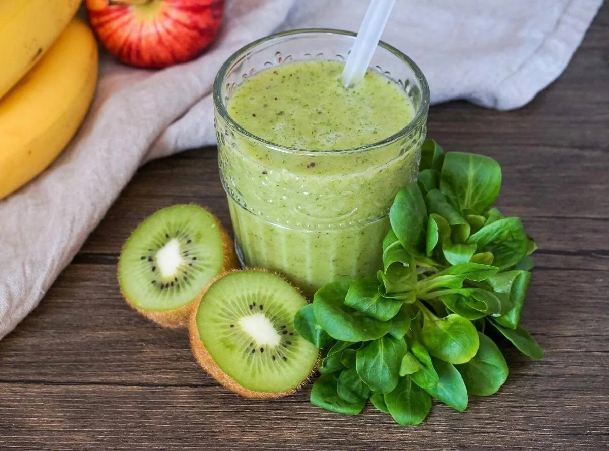 Grüner Smoothie mit Apfel und Banane in einem Glas mit Strohhalm