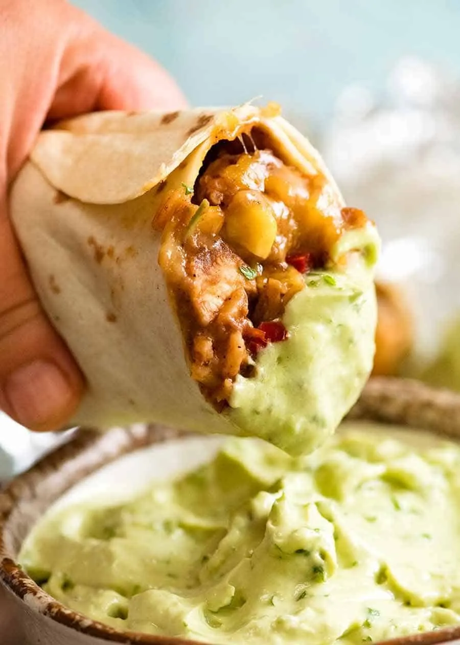 Hähnchen Burrito wird in eine cremige Avocado-Sauce getunkt