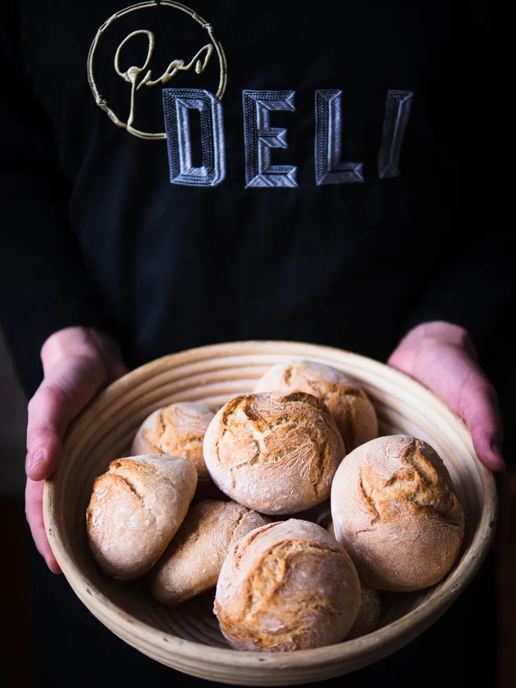 Hände beim Vermischen von Teigzutaten für Brötchen