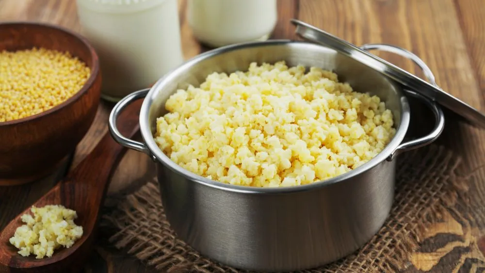 Hirse in einem Kochtopf mit Wasser und Gewürzen