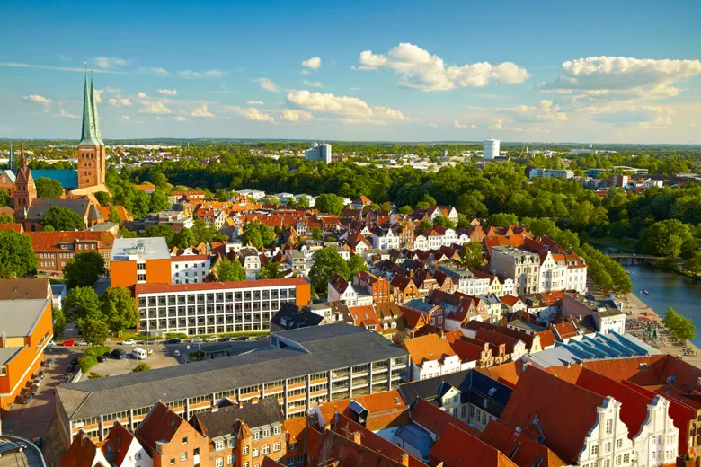 Historisches Holstentor in Lübeck mit seinen zwei markanten Rundtürmen, umgeben von grünen Bäumen