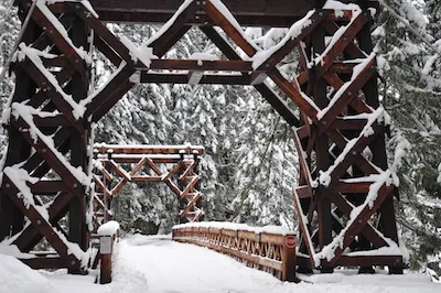 Holz-Hängebrücke mit einer Schneedecke bestäubt.