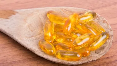 Holzlöffel mit Vitaminkapseln und Nahrungsergänzungsmitteln