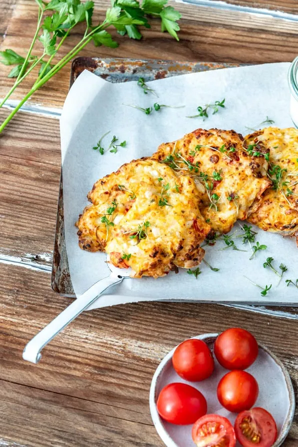 Hüttenkäsetaler mit Dip auf Backblech und einer Schüssel Tomaten