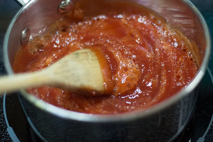 Ketchup in einem Topf auf dem Herd, mit deutlich sichtbarem Schaum nach Zugabe von Natron