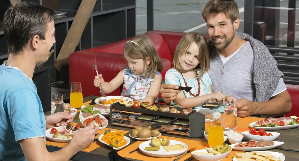 Kinder genießen einen Raclette-Abend mit bunten Zutaten