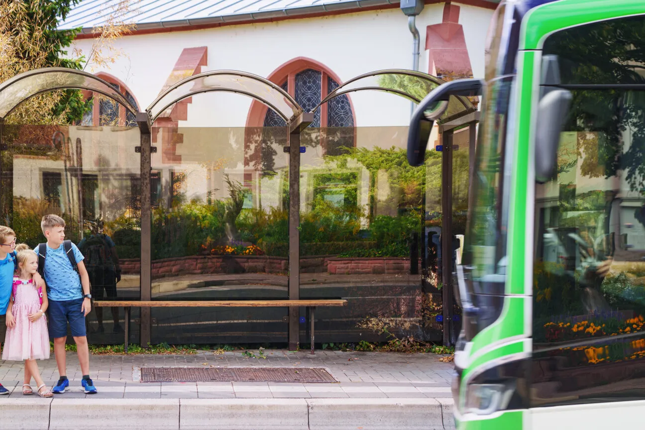 Kinder im Gespräch an der Bushaltestelle, warten auf den Schulbus.