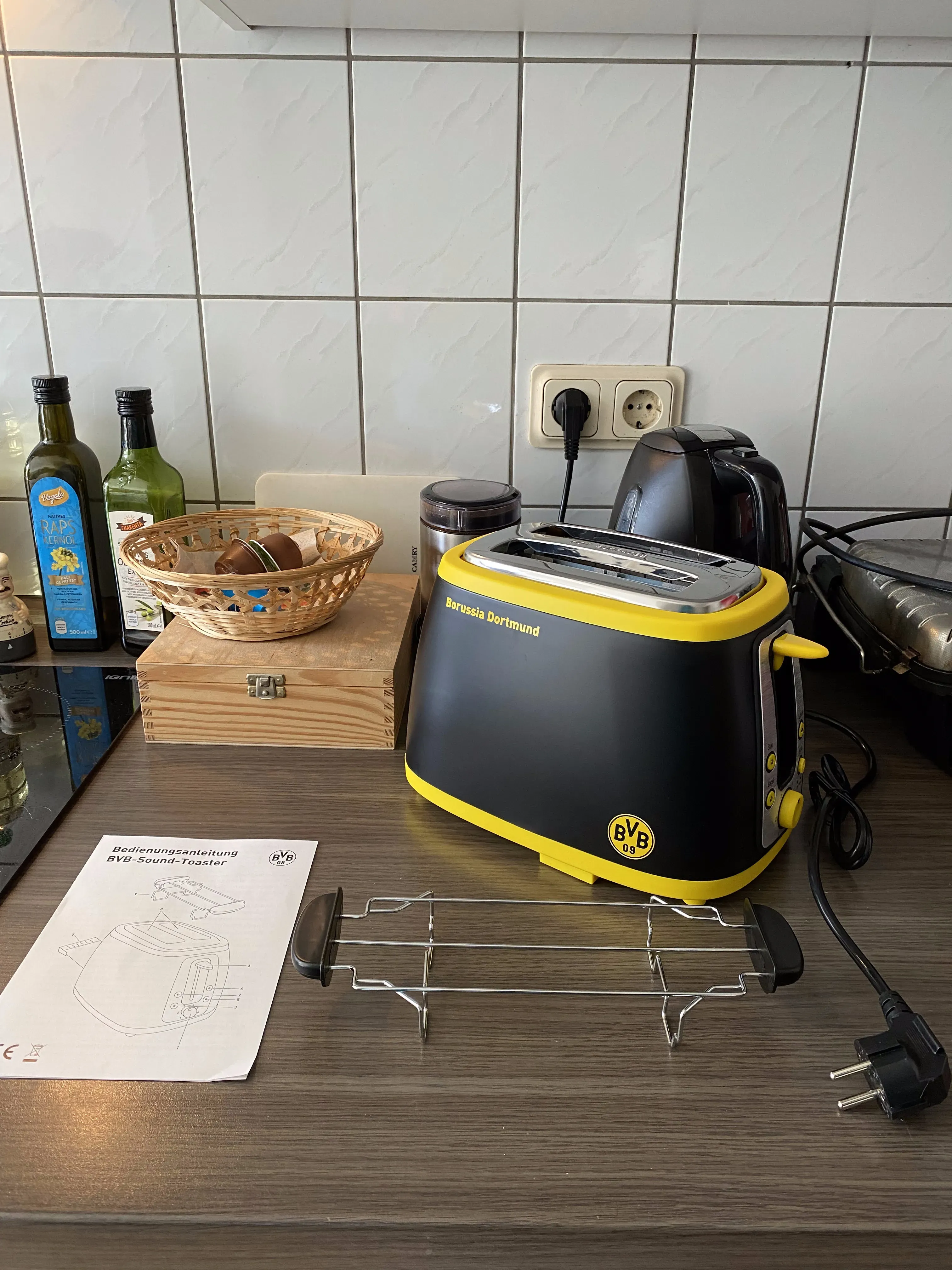 Klingender Toaster ausgepackt: Toaster, Brötchenaufsatz und Anleitung, die weitergegeben werden muss, falls man den Toaster jemals verschenkt.