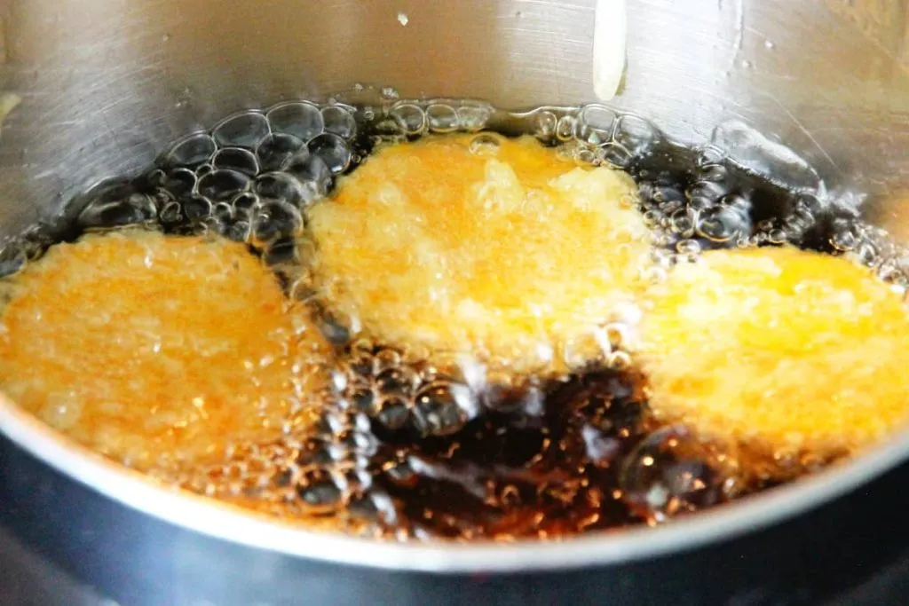 Knusprige frittierte Bällchen in heißer Sojasoße in einem Topf.