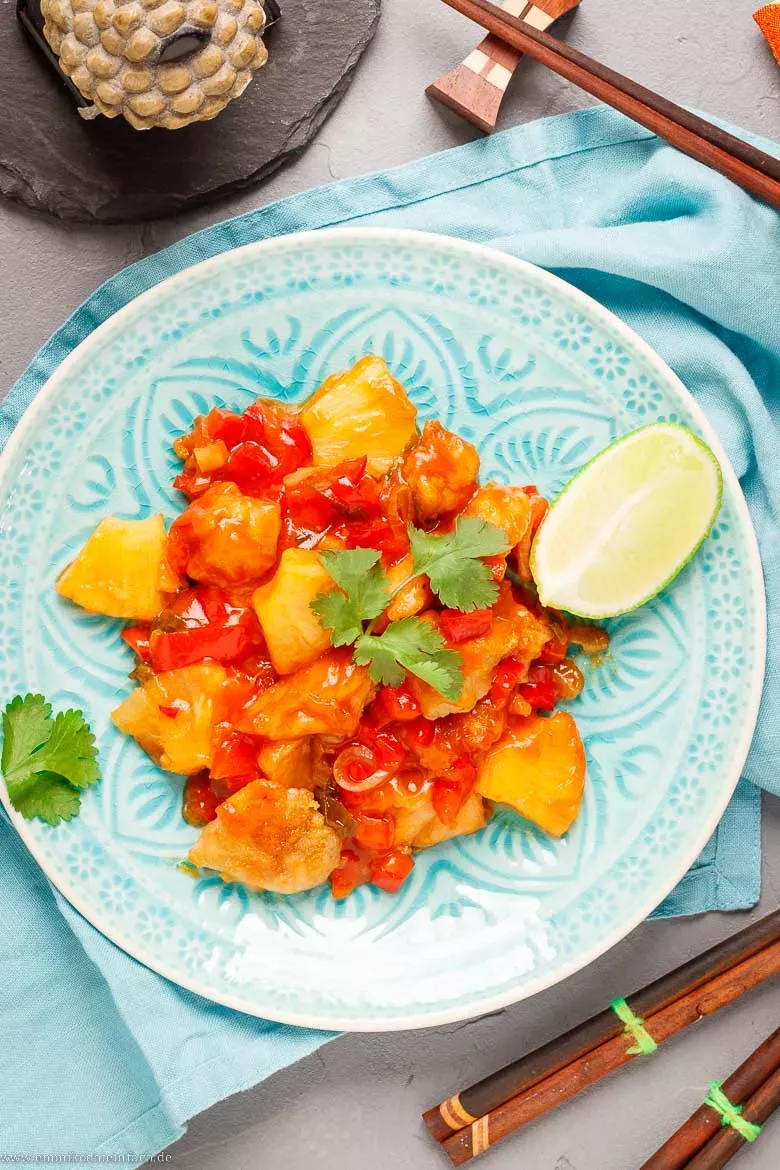 Knusprige Hähnchenstücke in süß-saurer Soße serviert mit Reis