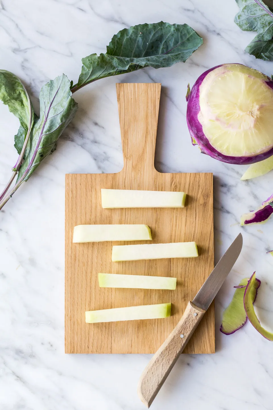 Kohlrabi-Pommes auf einem mit Backpapier ausgelegten Backblech, bereit für den Ofen