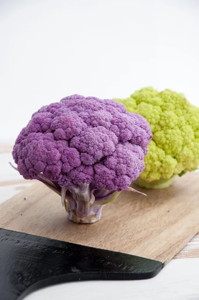 Lila und grüner Blumenkohl auf einem Schneidebrett