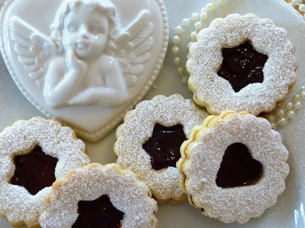 Linzer Plätzchen und ein Porzellanengel auf einem festlichen Teller