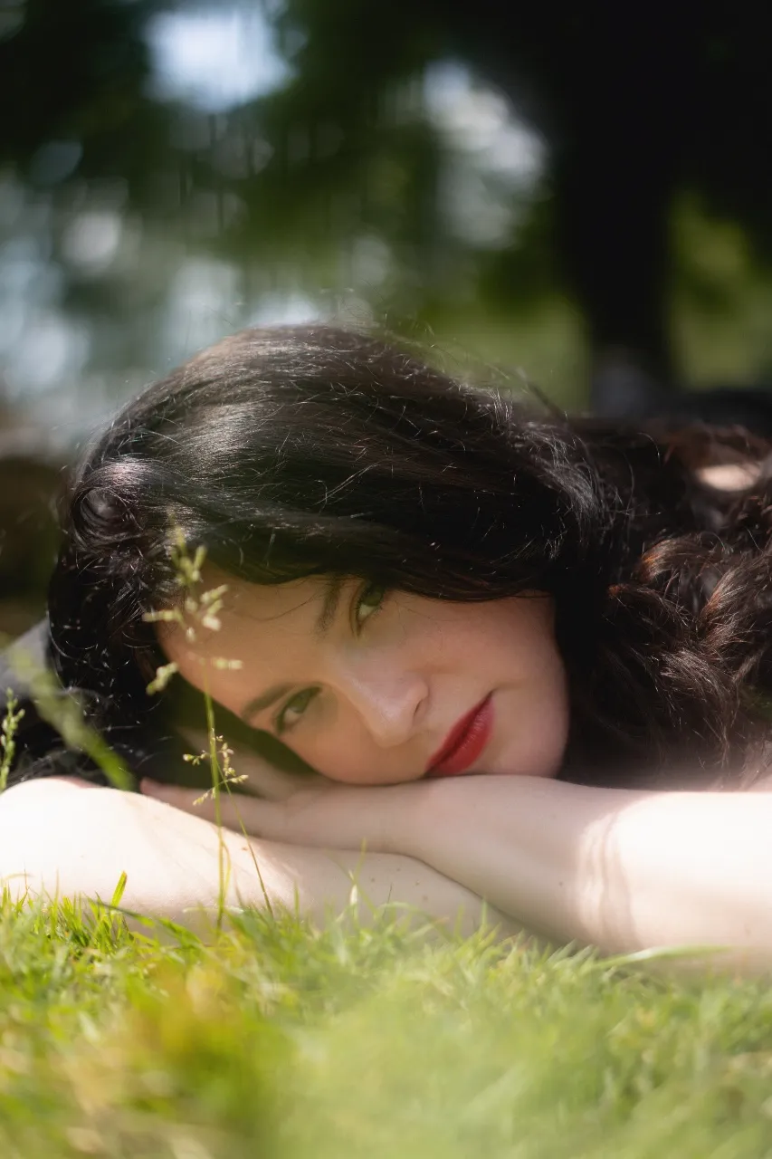 Lydia the Bard spielt eine Akustikgitarre vor einem unscharfen Hintergrund