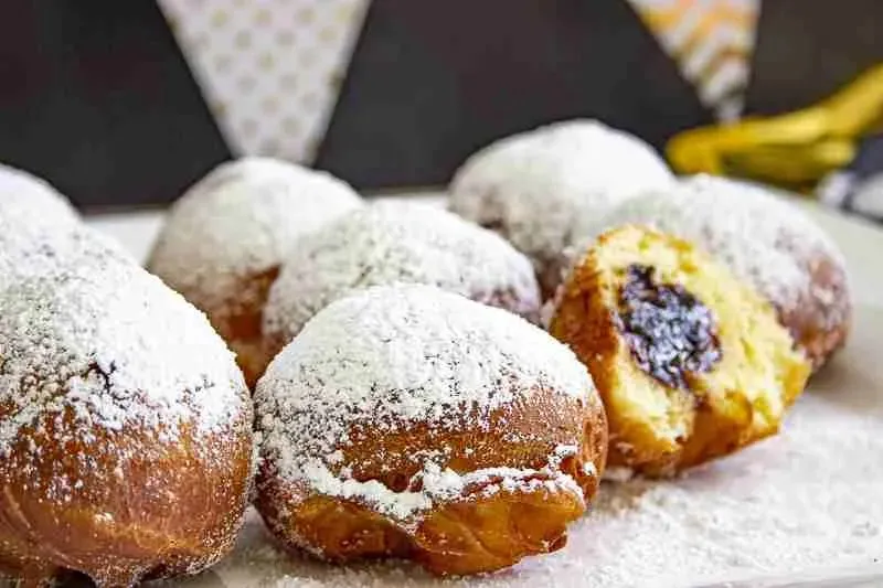 Mehrere Berliner Pfannkuchen auf einem Teller mit Puderzucker