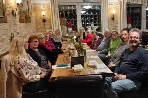 Mehrere Personen sitzen gemeinsam an einem gedeckten Tisch in einem Restaurant, es herrscht eine festliche Atmosphäre